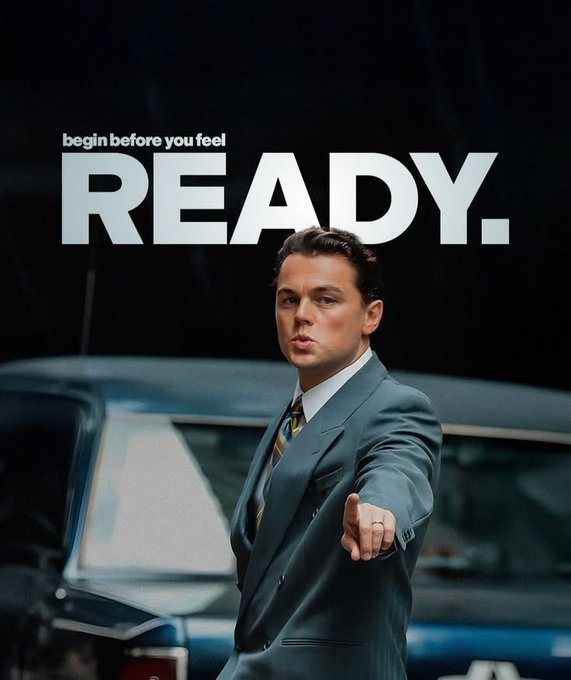 A motivational graphic featuring Leonardo DiCaprio in a grey suit pointing directly at the camera in front of a car, with bold white text reading 'begin before you feel READY.'