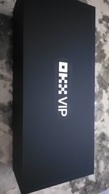 A sleek black box labeled "OKX VIP" sits on a marble surface, aligning with the post's reference to OKX VIP users receiving a special package to enhance their trading success.
