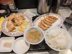 A meal from Gyoza no Ohsho (餃子の王将) featuring fried chicken (カツ), grilled gyoza, miso soup, and a bowl of white rice.