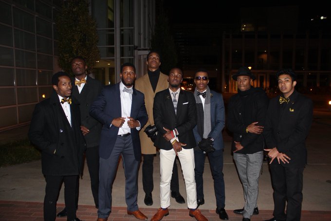 A group of seven well-dressed young men pose together at night, with several sporting bow ties and formal suits. The image appears to be a stylish group photo that has been associated with a 2016 nostalgia-themed post featuring the token identifier "2016" and the contract address "CqBK28r8JWrB7g3enXRmDayFGRs3kggwL37nfWA6pump."