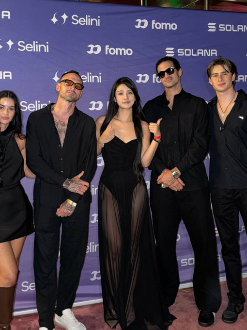 Five people pose on a red carpet in front of a purple backdrop featuring logos including 'Selini', 'fomo', and 'SOLANA'.