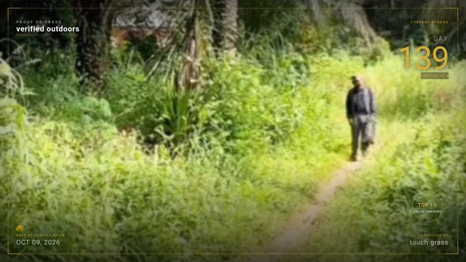 A low-resolution video still showing a person in a hat walking on a path through dense green foliage, with on-screen text reading 'verified outdoors', 'CURRENT STREAK DAY 139', and 'objective touch grass'.