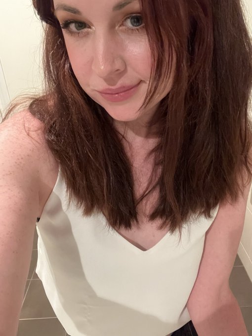 A woman with long auburn hair takes a mirror selfie while wearing a sleeveless cream-colored top, her expression confident and refreshed. The caption aligns with her upbeat "GM" post, as her poised, glowing appearance visually matches the energy of someone feeling renewed and ready to jump back in after stepping away.