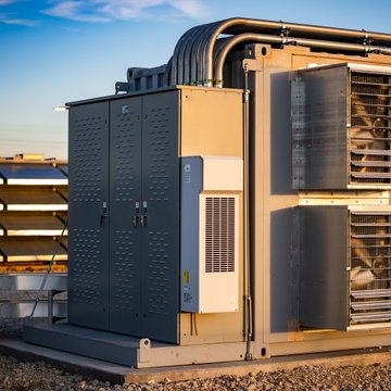 An industrial HVAC or generator unit sits on a rooftop with solar panels visible in the background.