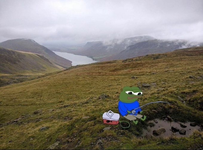 A meme featuring the Pepe the Frog character superimposed onto a scenic mountain landscape, depicted sitting on a folding chair fishing in a stream with a cooler beside him.