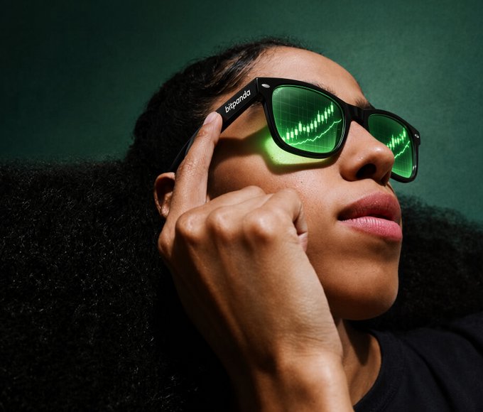 A stylized portrait of a woman wearing black sunglasses with green-tinted lenses that reflect a stock chart pattern, with 'bigmada' visible on the temple of the frames.