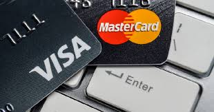 Visa and Mastercard credit cards rest on a keyboard near the Enter key. The image visually anchors the article's mention of these two payment giants among the global financial institutions backing the new Open USD stablecoin platform.