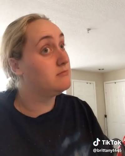 A TikTok video screenshot (@brittanyt445) showing a blonde person in a black shirt with wide eyes and a neutral expression in an indoor setting.