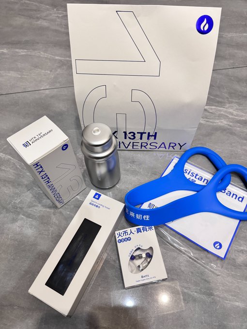 A collection of HTX 13th anniversary merchandise, including a metal water bottle, resistance bands, and a fan, displayed with their packaging.