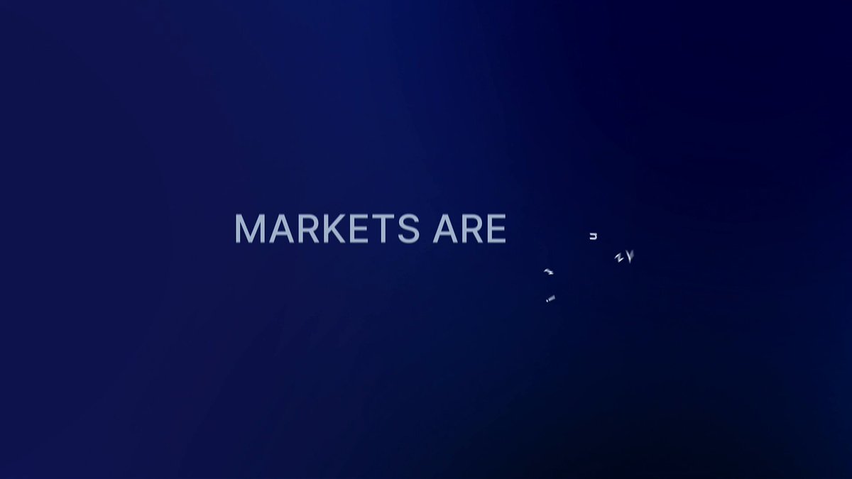 The image features a blue background with white text that reads "MARKETS ARE". The text is positioned at the top of the frame, drawing attention to its message. Below this, there are two small birds flying against the blue sky, adding a sense of movement and liveliness to the scene. The birds appear to be in flight near the bottom edge of the image, creating a dynamic element within the composition.