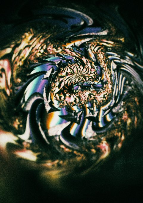 A warped, abstract close-up photograph featuring iridescent rainbow light refractions swirling against a dark background, creating a psychedelic, kaleidoscopic effect.