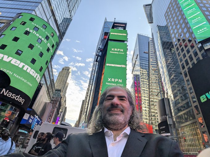 The poster, possibly taking a selfie, stands beneath the towering Nasdaq billboards displaying prominent advertisements for EverSmile and XRPN (Nasdaq: XRPN), with XRP referenced in the caption. The image captures the moment of anticipation or excitement associated with the stock's listing or performance.
