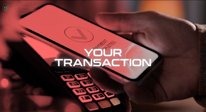 A stylized image with red lighting showing a hand holding a smartphone with a checkmark indicating a completed payment, overlaid with the text 'YOUR TRANSACTION'.