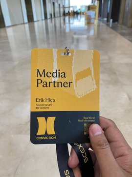 A hand holds a yellow "Media Partner" badge for Erik Hieu, Founder & CEO of DX Ventures, at the Conviction 2026 event in Ho Chi Minh City. The badge corresponds to the post announcing @ventures_bd's participation as a Media Partner at the Vietnam Digital Asset & AI Economy Forum.