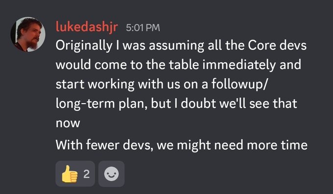 A Discord message from user "lukedashjr" posted at 5:01 PM states: "Originally I was assuming all the Core devs would come to the table immediately and start working with us on a followup/long-term plan, but I doubt we'll see that now. With fewer devs, we might need more time." The post received 2 reactions (👍 and a smiley face). This relates to the caption's skepticism, as Luke Dashjr's comments about Bitcoin Core developers potentially not cooperating show a disconnect from expectations of unified collaboration—critics would view his assumptions about Core devs' willingness to "come to the table" as disconnected from the reality of a divided developer community.