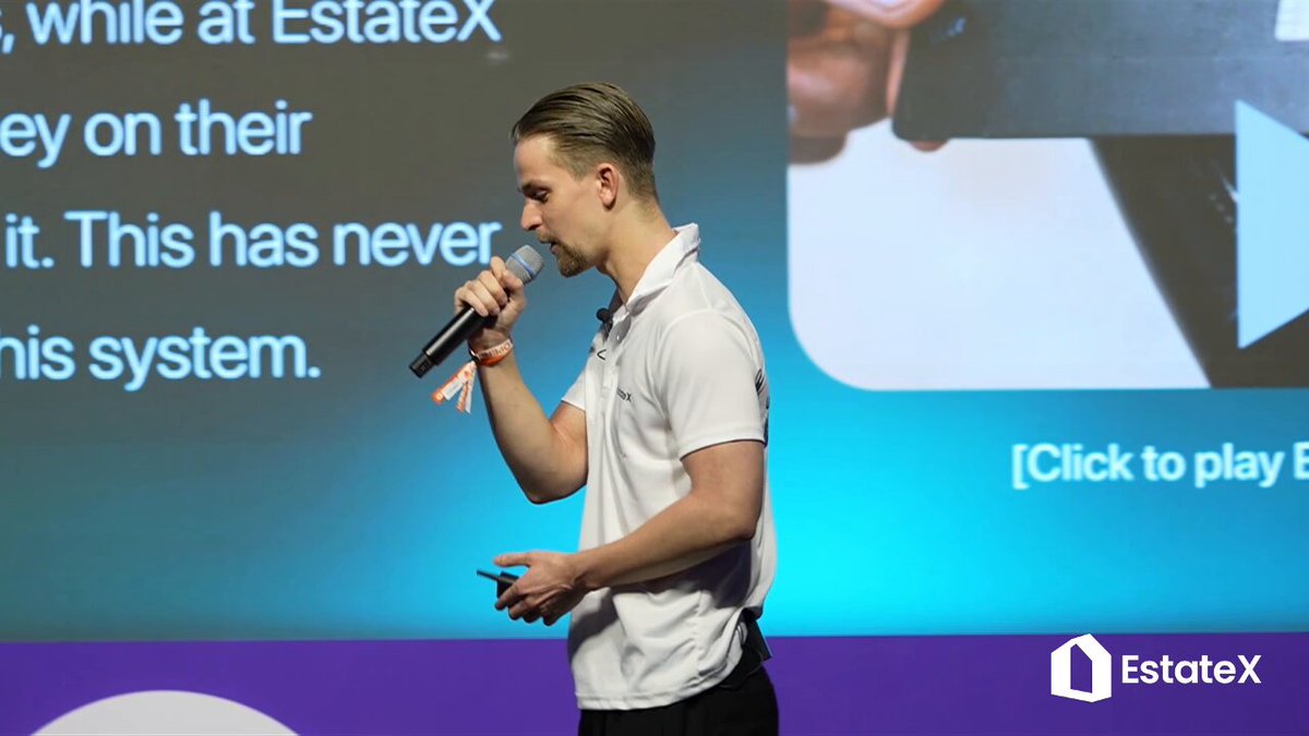 The image features a man standing next to a screen, holding a microphone and speaking into it. The background of the image shows a banner that says "EstateX Pay" with an image of a house below it. The text on the banner indicates that EstateX is closing the gap between liquidity and real estate by allowing users to earn from their property investments directly using their EstateX card, which can be used for spending purposes as well.