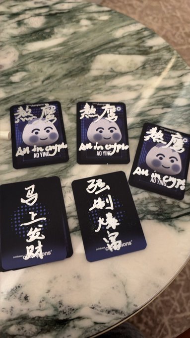 Five panda-themed cards reading "热魔 All in crypto AO YING" are displayed alongside two calligraphy cards wishing "马上发财" and "多刷多得" on a marble table, with one card branded "celebrating connections" — hand-signed giveaways for a social media contest.