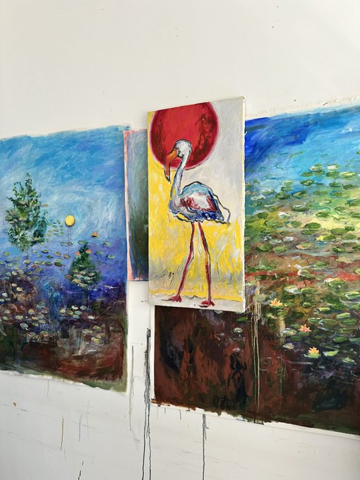 Multiple paintings hang on a white wall, with a central piece depicting a flamingo-like bird with a red head standing on a yellow background, flanked by landscape paintings featuring trees and water.