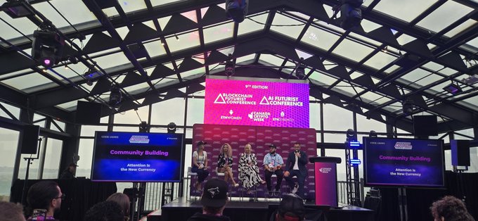 A conference panel at the '8th Edition Blockchain Futurist Conference' in Toronto, with panelists seated on a purple couch under banners reading 'Community Building: Attention is the New Currency'.