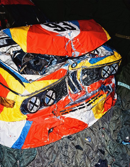 A deflated, colorful red, white, blue, and yellow parachute or kite with the number '05' printed on it lies crumpled on a dark green fabric.