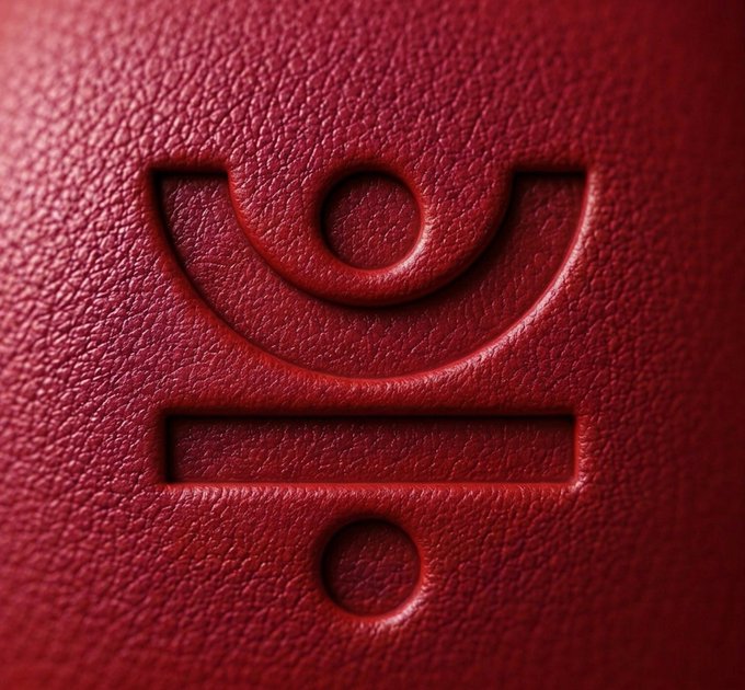 A close-up macro shot of the red leather-textured "J" logo of the JUST DeFi ecosystem, symbolizing the unified, interconnected nature of the platform. The embossed emblem visually reinforces the post's message about how every component within the JUST ecosystem works together as one cohesive whole.