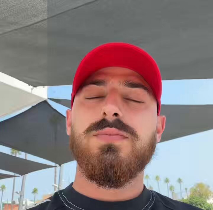 In the image, a man with a beard wearing a red hat is posing for a photo while looking away from the camera. The background features multiple umbrellas of varying sizes. The caption on the image reads "Bullish on Moonpot $100,000 USDC probably huge giveaways soon". The text and visual elements suggest that the man might be taking part in a large giveaway or contest related to cryptocurrencies, as indicated by the "Moonpot" reference.