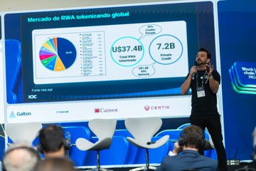 A man in a black shirt speaks into a microphone at a conference, presenting a slide titled 'Mercado de RWA tokenizando global' showing US$37.4B and 7.2B figures, with sponsor logos including IDC, Galton, Casaneve, and CERTIK visible below.
