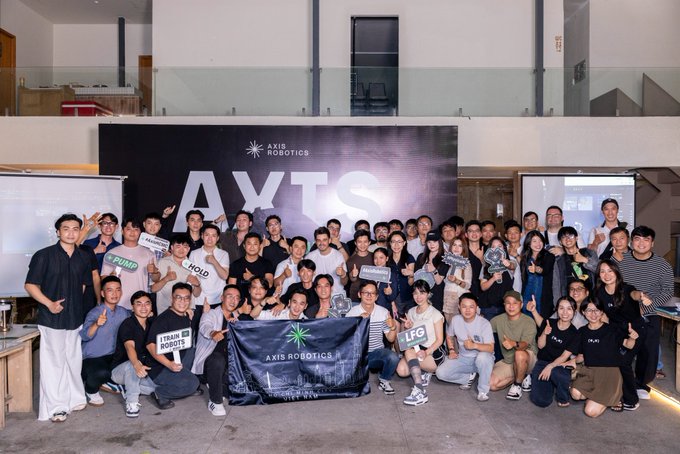 A large group photo of attendees at an Axis Robotics event, posing with branded flags and signs including 'PUMP', 'HOLD', 'LFG', and 'TRADE ROBOTS'.