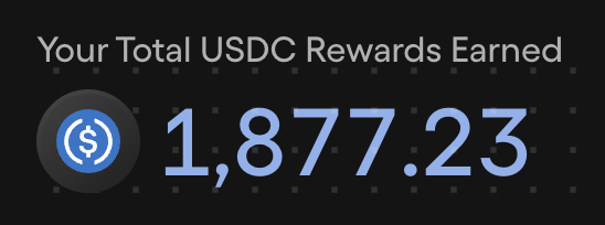 The image shows a black and white sign that displays the total USDC rewards earned by a user. The text on the sign reads "Your Total USDC Rewards Earned" with numbers 1,877,723 displayed below it. The background of the sign is gray, providing contrast to the white text.