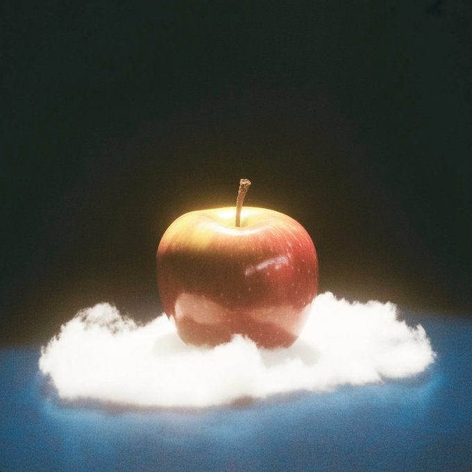 A red apple rests on a small white cloud against a dark background, evoking a surreal "fruit of dreams" concept that visually represents the imaginative theme of the NFT artwork being auctioned.