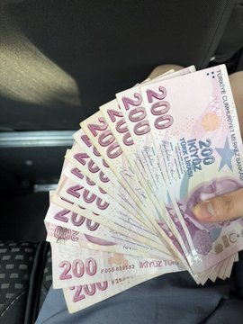 The image shows a person holding a stack of 200 Turkish lira bills, which are worth $ETH. The person's hand is visible as they hold up the money. The photo also includes text that reads "已知刚刚取了8000里拉 为刚刚好够155欧 乐值的速度高于土耳其里拉都不如的垃圾 请大声告诉我为什么要抄底？", which is likely a caption or description of the image.