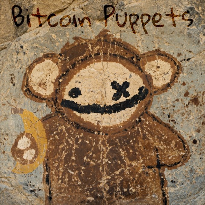 A cave painting-style illustration depicts a teddy bear with an 'X' for one eye and a wide grin, titled 'Bitcoin Puppets' written above in red, alongside a yellow Bitcoin symbol.