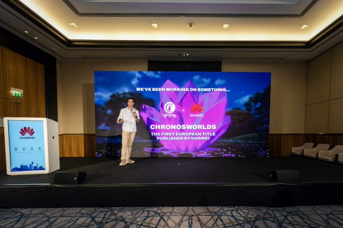 A man in a beige suit speaking on stage at a Huawei event, with a large screen behind him announcing 'CHRONOWORLDS - THE FIRST EUROPEAN TITLE PUBLISHED BY HUAWEI' alongside the geneLife logo.
