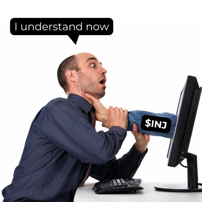A startled-looking man sits at a computer monitor saying "I understand now" as he strangles himself with his own tie. The image humorously depicts the misguided panic of mistaking $INJ for $INJC, with the "$INJ" label visible on his tie.