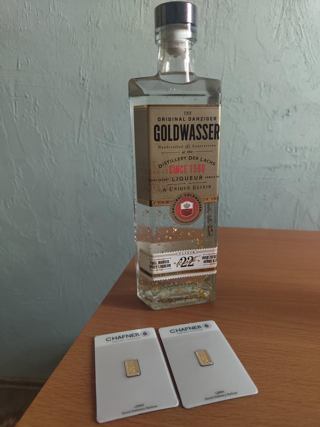 A bottle of 'The Original Danziger Goldwasser' herbal liqueur (since 1598) from Distillery Der Lachs, displayed with two small Chafner gold delivery bars (1.25MB and 1.25MA).