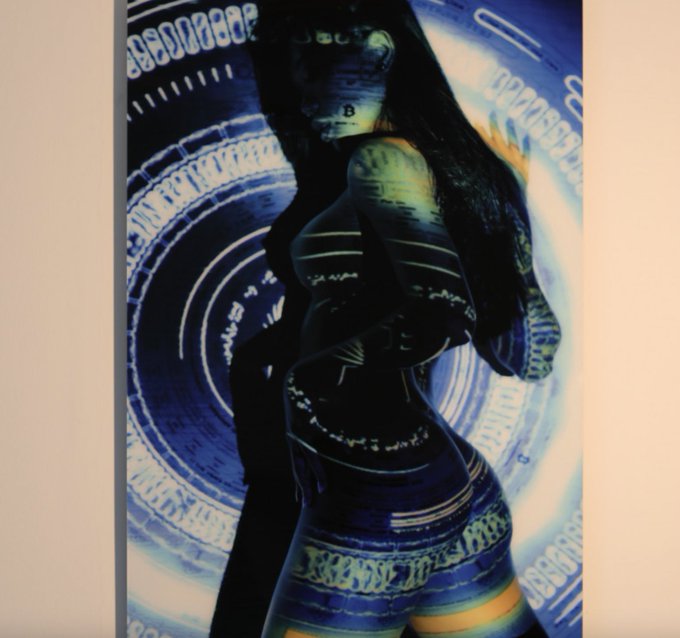 The image features an artist's portrait of a woman with long hair, wearing a black dress that has blue stripes. She is standing against a white background, which contrasts with her dark attire. The painting is displayed prominently in a gallery setting, drawing attention from viewers who are captivated by the unique and striking artwork.