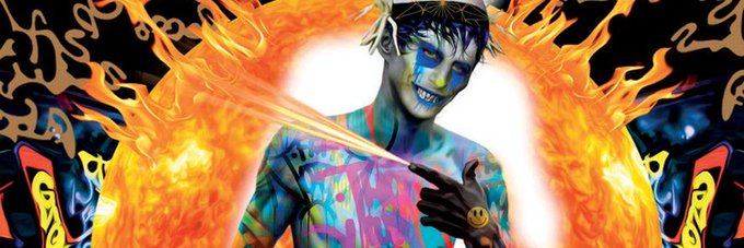 A vibrant psychedelic-style portrait of a shirtless man with blue face paint and a grinning smile, surrounded by colorful flames and a large glowing halo.