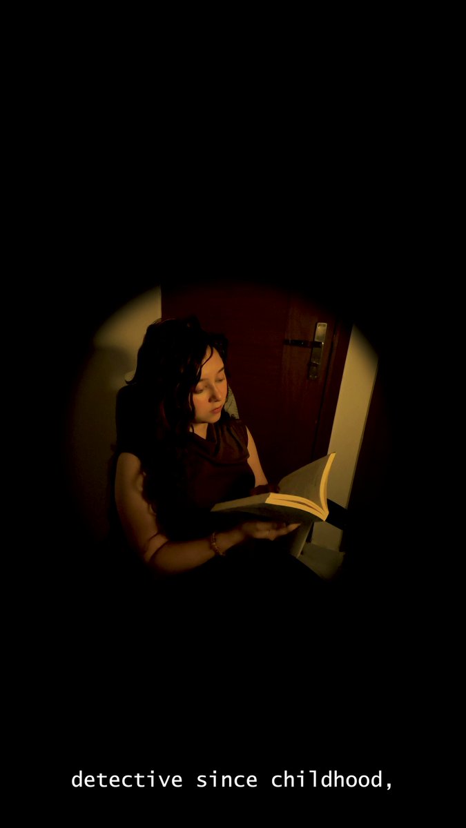 The image features a woman sitting down, reading an open book with a serious expression on her face. The background of the image is dark, which adds to the atmosphere of mystery surrounding the scene. There are two lines of text at the bottom of the image that read "detective since childhood, detective". This phrase seems to be related to the woman's situation and could possibly be a reference to her current life or past experiences.
