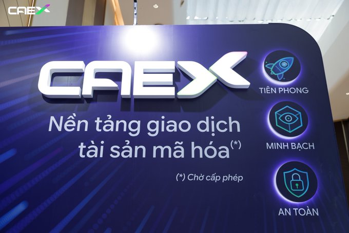 The image showcases the CAEX booth at the KOL Summit 2026, featuring a vibrant blue display with the "CAEX" logo and its tagline in Vietnamese: "Nền tảng giao dịch tài sản mã hóa" (Crypto Asset Trading Platform) marked with "(*) Chờ cấp phép" (Awaiting licensing). Three key brand pillars are highlighted with icons—**TIẾN PHONG** (Pioneering), **MINH BCH** (Transparency), and **AN TOÀN** (Security)—reflecting CAEX's commitment to innovation, transparency, and safety in the digital asset space. This visual ties directly to the post's mention of CAEX's active presence at the summit, where participants engaged in a crypto asset challenge, exchanged market insights, and experienced high-energy collaboration at the booth.