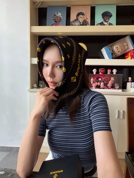 A woman poses while wearing a black Binance-branded silk scarf, part of a Binance 9th anniversary gift box.