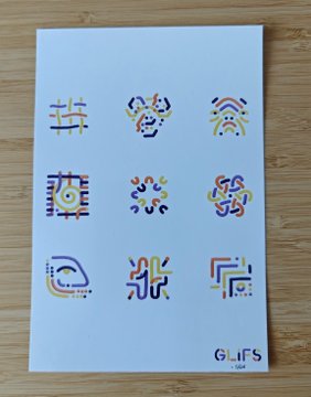 The image features a white paper with various colorful designs, including circles, lines, and shapes, arranged in a grid-like pattern. The designs are predominantly yellow, orange, purple, and blue, creating an eye-catching and vibrant display of artistry. The text "GLiFS" is also present on the paper, possibly indicating that this artwork was created by @EfdotStudio or someone associated with them.