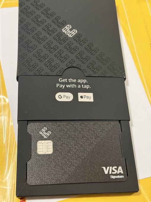A black metal credit card branded with a VISA Signature logo and chip, presented in a black sleeve reading "Get the app. Pay with a tap." alongside Google Pay and Apple Pay logos.