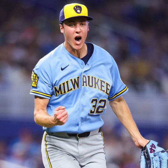 A Milwaukee Brewers baseball player, wearing jersey number 32 and a light blue uniform, celebrates with a clenched fist and open mouth.