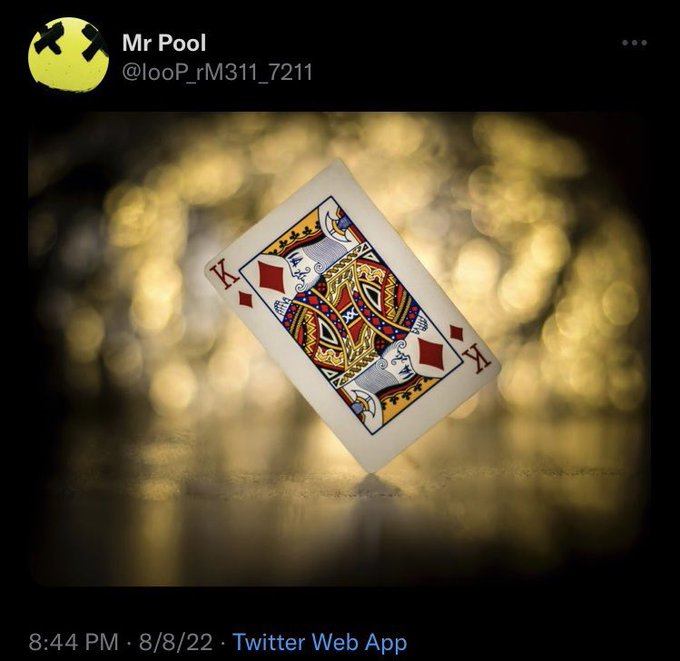 A Twitter post from user 'Mr Pool' (@looP_rM311_7211) dated 8/8/22 featuring a photo of a King of Diamonds playing card balanced on its edge against a bokeh golden background.