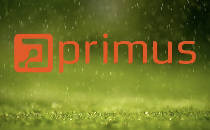 A logo for 'primmus' in bright orange lowercase text with a stylized icon on the left, set against a blurred green background of grass with water droplets.
