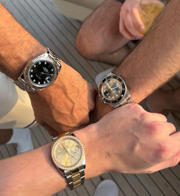 Three wristwatches—a Rolex Datejust with a black dial and diamond markers, a Rolex Submariner with a black bezel, and a Rolex Turn-O-Graph with a champagne dial—are displayed on their owners' arms, accompanied by the caption "We're just up too much" playfully suggesting the group has had a bit too much to drink.