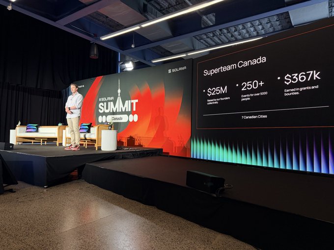 A speaker presents at the Solana Canada Summit, with a slide highlighting Superteam Canada statistics including $25M raised for business initiatives, 250+ events for over 5000 people, and $367k earned in grants and bounties across 7 Canadian cities.