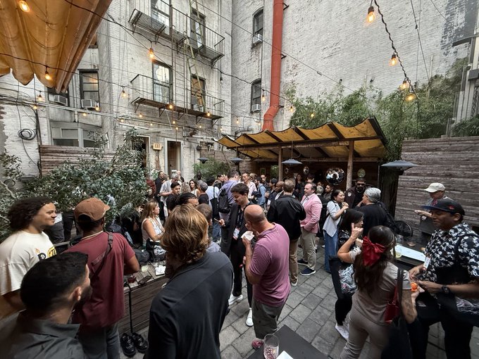 A lively crowd gathers in a charming NYC courtyard strung with warm string lights, mingling and enjoying drinks under a covered pavilion—capturing the vibrant atmosphere of the Pangolin × @TheArenaApp After Hours event during Avalanche Summit. The scene embodies the post's celebration of community, meaningful conversations, and an impressive turnout of engaged attendees.