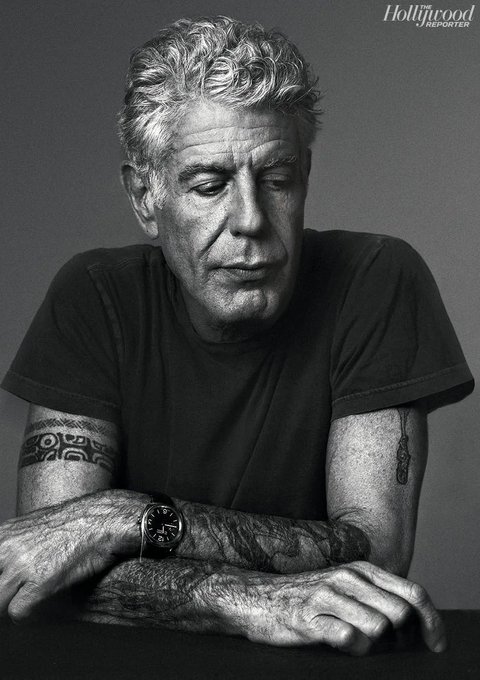 The image features an older man wearing a black shirt, sitting at a table with his arms crossed over his chest. He has a tattoo on his arm and a watch on his wrist. The photo appears to be from a magazine or newspaper, as indicated by the caption "find the next fidenza or the fidenza after that crank hog to machine slop. floor a grail. submit to the prospect of a world existing solely of eternally diminishing derivatives." This caption suggests that the man is described in a negative light and may be associated with a particular subculture, such as the hipster movement.