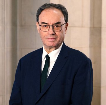 An official portrait of a man in a dark suit, white shirt, and dark tie, wearing glasses and smiling slightly.